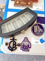 Watch case exterior with clear lid and three embroidered patches laid below