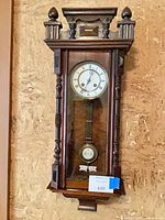 Full view of wooden wall clock hanging on wall