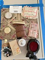 Group shot of entire lot showing all sewing notions, cologne bottle, boxes, tape measure, doll, pin cushion