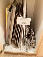 Vertical stack of various baking sheets, cooling racks and pans in cabinet