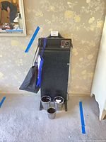 Full view of trouser press, hanger attached, totes hanging on side, three metal pots on floor