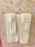 Four cotton terry towels with lace and ribbon trim hanging on rod