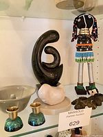 All items in lot on shelf: abstract sculpture, ceramic form, beaded doll, candle holders, bowl and carved wooden pieces