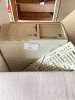 Front angled view of beige PC tower with floppy and optical drives, wired keyboard visible