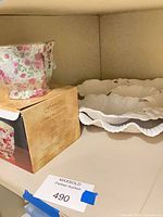Floral cachepot candle with box and ruffled platter on shelf