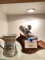 Koala figurine and stoneware mug together on shelf
