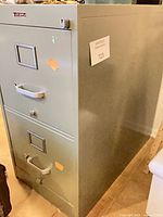 Full view of gray metal 2-drawer filing cabinet showing handles, label plates and lock