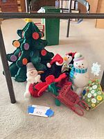 Group view of felt trees, plush figures, wicker sleigh and poinsettia stems