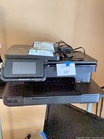 Front view of HP Photosmart 7520 printer with power cord and boxed cartridges on top