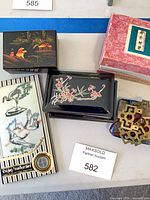 Overview of all items: two lacquer boxes, packaged handkerchief, pink Fujian box, brass ornaments