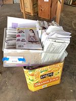 Plastic bin filled with numerous sewing pattern envelopes inside cardboard box