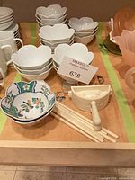 Stacks of white scalloped bowls, floral bowl, chopsticks and dumpling press overview