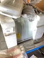 oven inside styrofoam with accessories on and beside unit