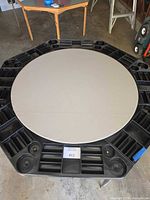 Full view of round poker tabletop showing beige playing surface and black plastic rail with built-in chip trays and cup holders