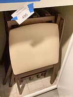 Stacked beige-seat wood chairs in storage