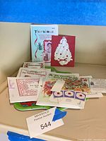 Stack of thimble booklets, Santa card and green plates on table