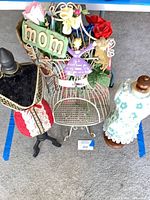 Lot overview showing two dress forms, wire birdcage with flowers and signs