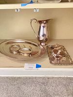 Pitcher, oval platter with tree well, two small dishes displayed on shelf