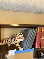 Tiger figure on shelf beside slate-blue hardbound books