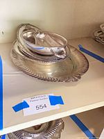 Stack of silver-plated serving pieces on shelf