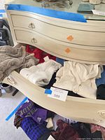 Open drawer with grey sweater, white garment, assorted clothing pieces visible