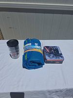 Tumbler, rolled mat, closed tin on table