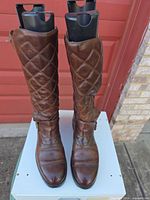 Front view of brown leather Ralph Lauren knee-high riding boots on stand