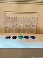 Five wine glasses lined up showing frosted bowls, twisted stems and multicolor bases