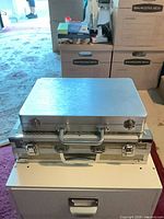 Two views of closed silver aluminum cases stacked, focus on size and exterior finish