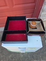Black/red organizer tray next to small leather tray with baseball