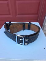 Overall view of belt showing chrome buckle, basket-weave pattern, tan lining