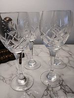 Four cut-crystal wine glasses on marble surface