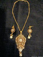 Full view of necklace and both earrings laid flat