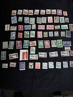 Overview of 70 loose Greek stamps spread on dark cloth