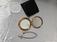 Open Kigu compact, loose sifter, necklace with cross pendant, black pouch