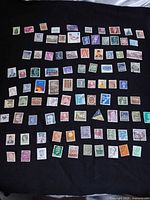 Full set of 90 worldwide stamps spread on dark cloth