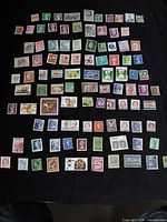 Entire spread of roughly 100 mixed-country stamps on black background