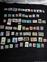 Overview of roughly 70 assorted stamps laid out on black cloth