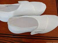 Top view of both white mesh slip-on shoes