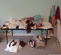 overall view of table with assorted fabric, box of more fabric below