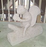 Full view of stone squirrel sculpture on log, front angle