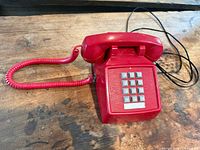Top view of red corded telephone showing full base and handset