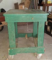 Front view of green wooden cart table with casters