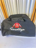 Front view of black Saratoga duffel showing logo and handles