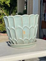 Side view showing seafoam glaze, petal relief, attached saucer, small chip visible