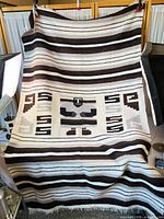 Full view of woven blanket showing overall stripe pattern and central motif