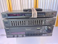 Front view of stacked Technics SU-V98 amplifier, SH-8017 equalizer, ST-S98 tuner with remote and bundled cords on top