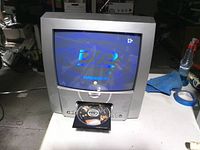 Front view of Magnavox CRT TV with DVD tray open and disc loaded showing DVD logo on screen