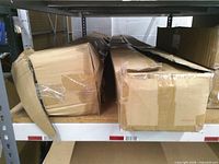 Two long cardboard boxes on shelf, one partially collapsed