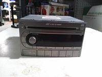 Front view of Panasonic 6-disc CD car stereo showing faceplate, controls and disc slot